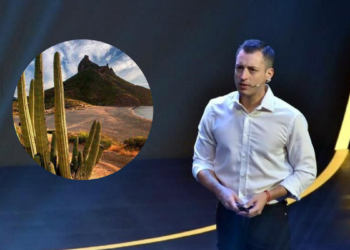 Male Presenter in a White Shirt on a Dark Stage; Circular Inset Shows a Desert with Tall Cacti and Rocky Hills in the Distance. | Ciudadano Seguros