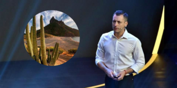 Male Presenter in a White Shirt on a Dark Stage; Circular Inset Shows a Desert with Tall Cacti and Rocky Hills in the Distance. | Ciudadano Seguros